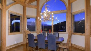 A dining room with a wooden ceiling, large windows, and a chandelier. - Chateau Renard (Crested Butte)