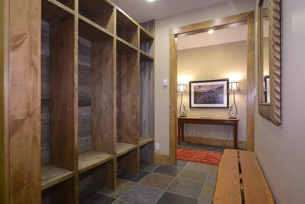 Un couloir avec des étagères en bois, un banc, un tableau encadré posé sur un chevalet et un miroir accroché au mur.