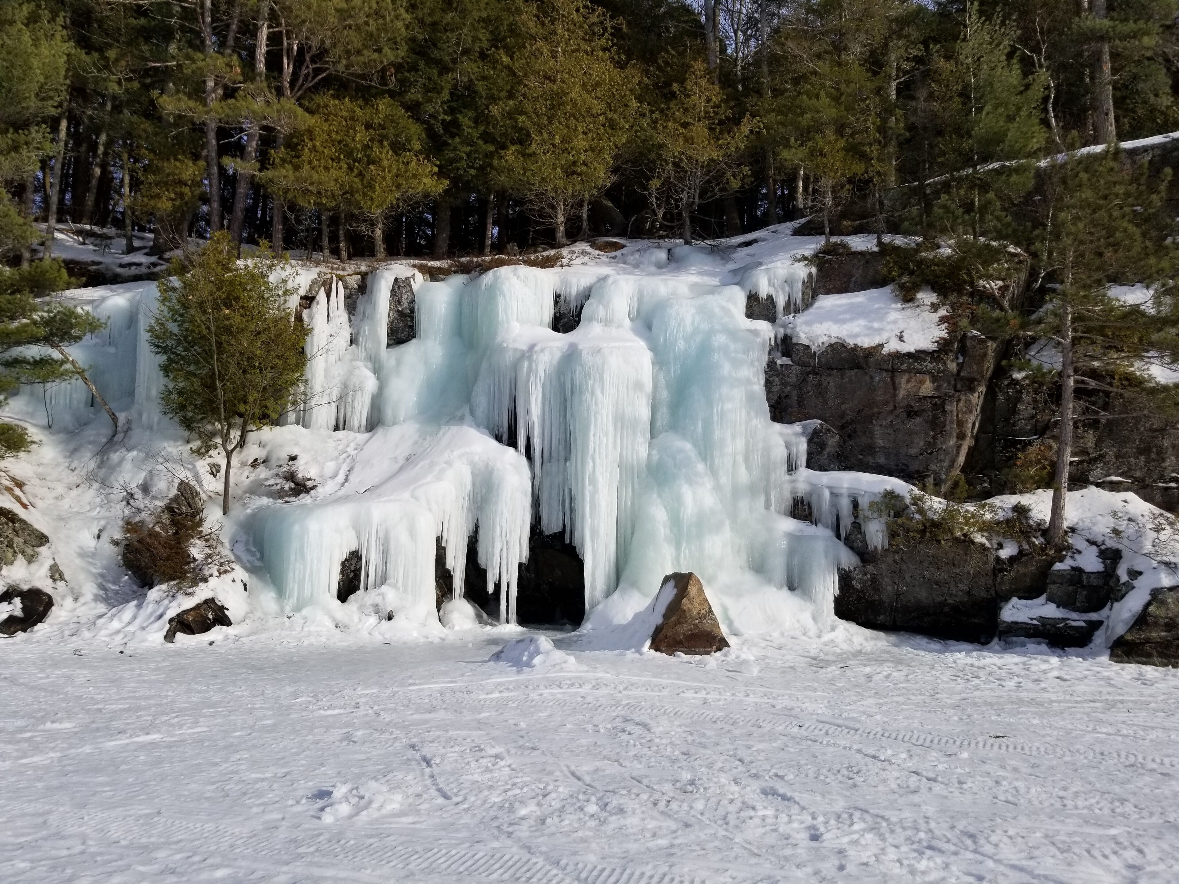 A waterfall cascading over rocks in a snowy forest.