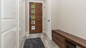 A hallway with a wooden door featuring glass panels, a bench, and a rug. - Lake Rosseau - Rare, Flat double lot with breathtaking South West views. (Minett)