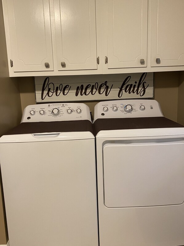 A laundry area with two front-loading washing machines and a sign above them that reads "love never fails." - 333 is 5 minutes from the dam with boat launch and tritoon boat for rent. (Jasper)