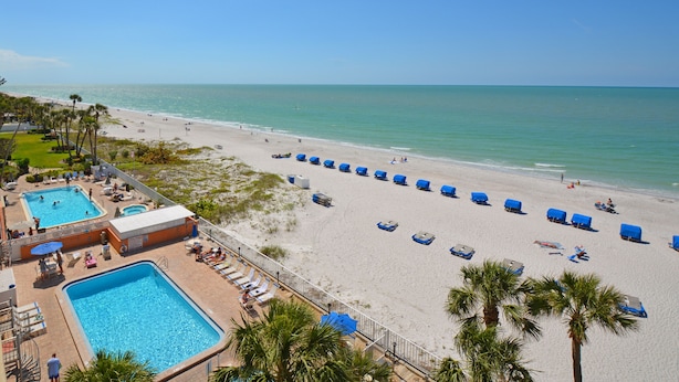 Un resort con piscina, sillas de playa y vista al océano.