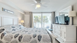 Un dormitorio con cama, ventilador de techo, televisor y cómoda.