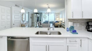 Cocina moderna con una isla central, pileta de acero inoxidable e iluminación colgante.