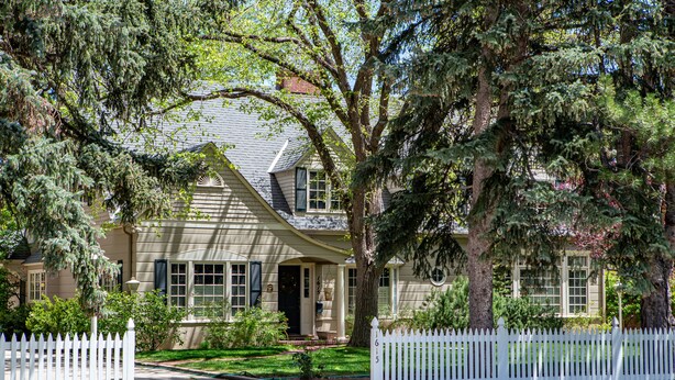 A two-story house with a white picket fence, a front porch, and a well-maintained lawn. - The Best VRBO In Colorado Springs.  Our Reviews Prove It.  Near All The Venues  (Colorado Springs)