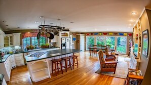 A spacious kitchen with a central island, wooden flooring, and a dining area with chairs and a table. - The Best VRBO In Colorado Springs.  Our Reviews Prove It.  Near All The Venues  (Colorado Springs)