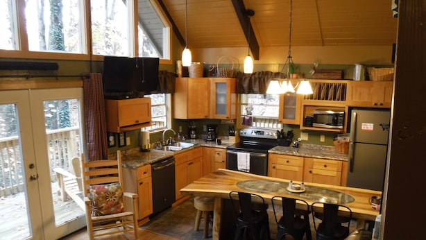 Une cuisine chaleureuse avec des meubles en bois, un îlot central et un coin repas comprenant un canapé et des fauteuils.