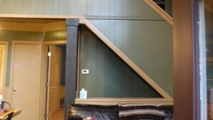 Un salon chaleureux avec un canapé en cuir noir, un escalier en bois et un mur vert.