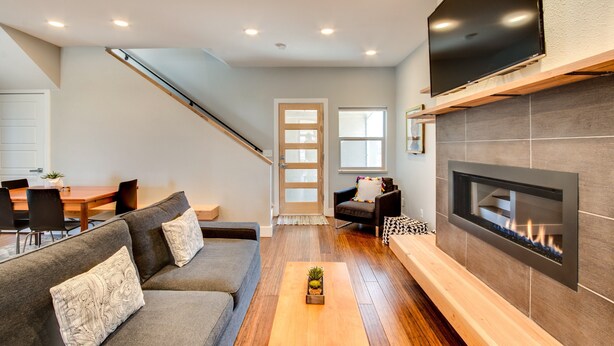 A modern living room with a fireplace, a sofa, a coffee table, and a TV mounted on the wall. - Downtown Views and Brews (Fort Collins)
