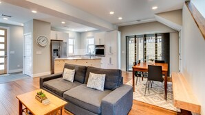 A modern living room with a grey sofa, wooden coffee table, and a dining area with a wooden table and chairs. - Downtown Views and Brews (Fort Collins)