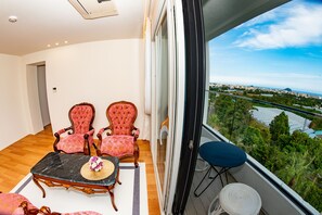 Enjoy a panoramic city view from this spacious balcony with a large window, featuring a river and distant mountains.