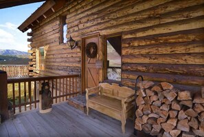A wooden cabin with a porch, a bench, a lantern, and a stack of firewood. - Bear Vista (Crested Butte)