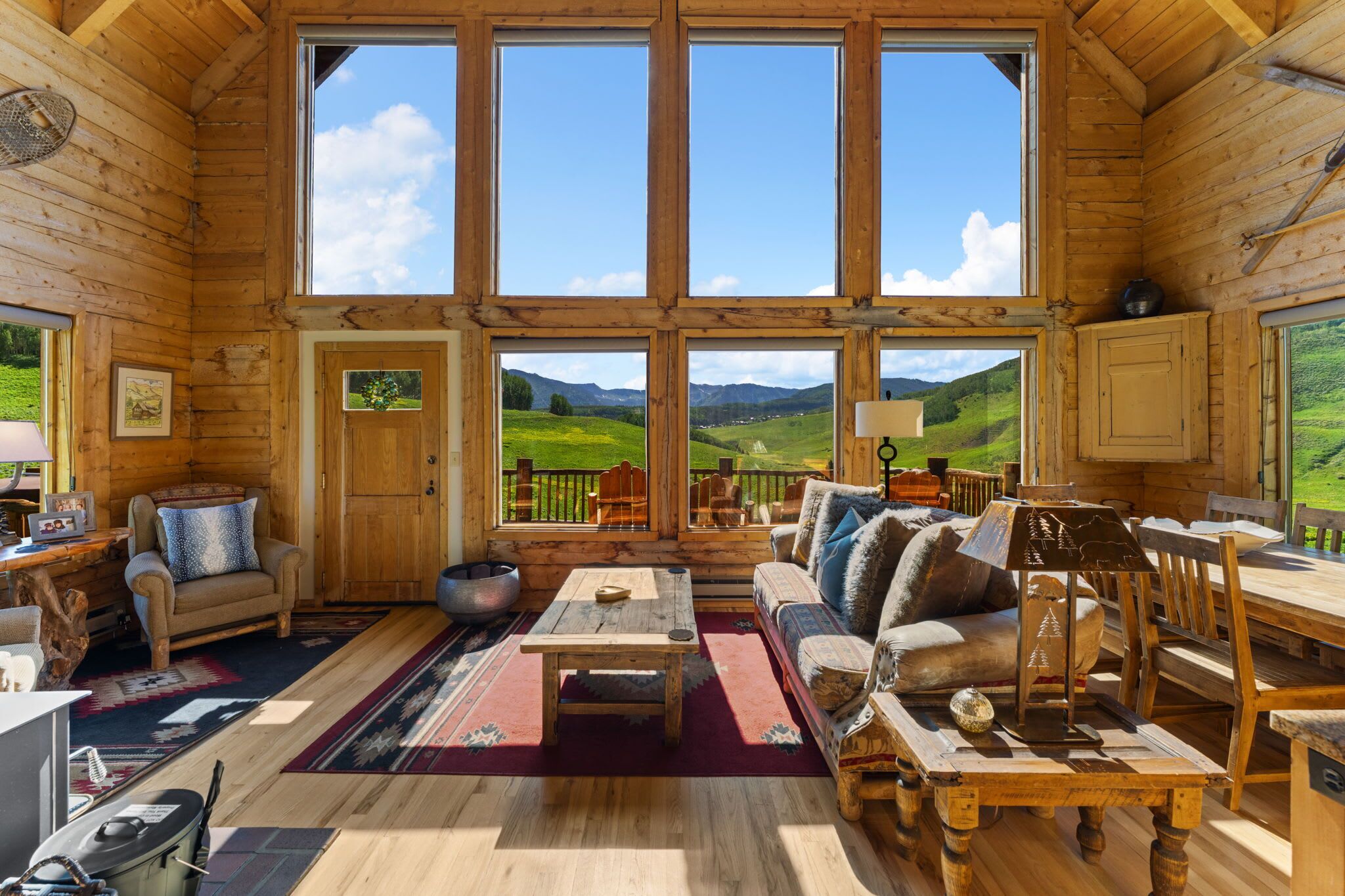 A wooden cabin interior with a large window overlooking a green landscape.