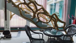 A modern interior with a unique wooden wall design, wicker furniture, and a view of the outside. - Prdeiction Hotel (Guilin)