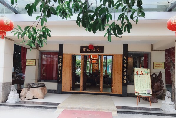 A traditional Chinese building entrance with wooden doors, red lanterns, and a signboard.