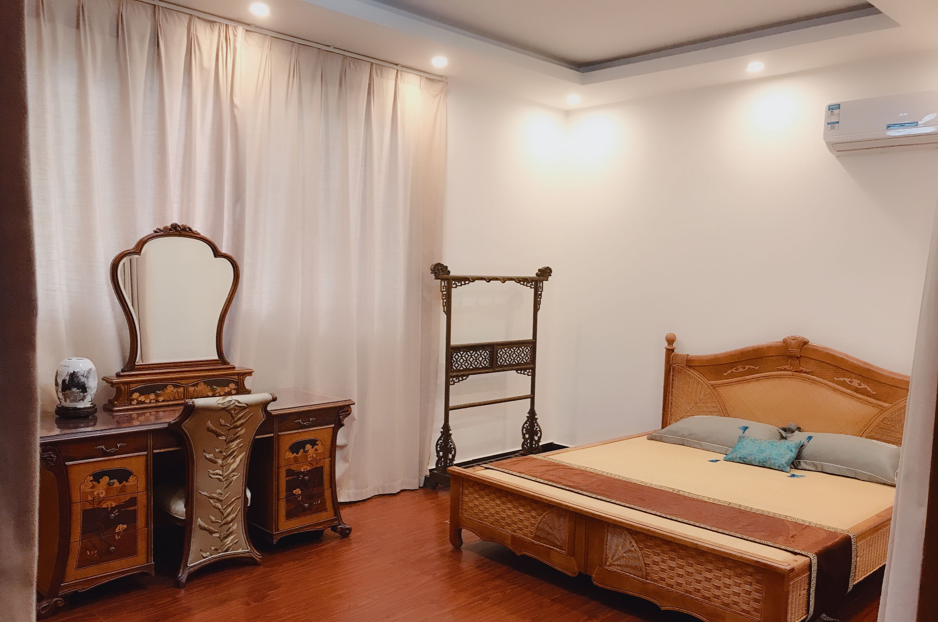 A bedroom with a wooden bed, a nightstand, a dresser, and a mirror.