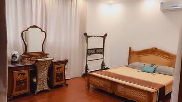 A bedroom with a wooden bed, a nightstand, a dresser, and a mirror.