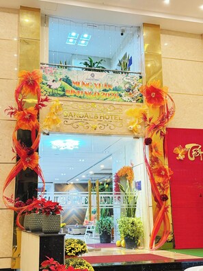 A hotel entrance with a decorative archway, a banner for an event, and potted plants. - Sandals Hotel (B'Lao)