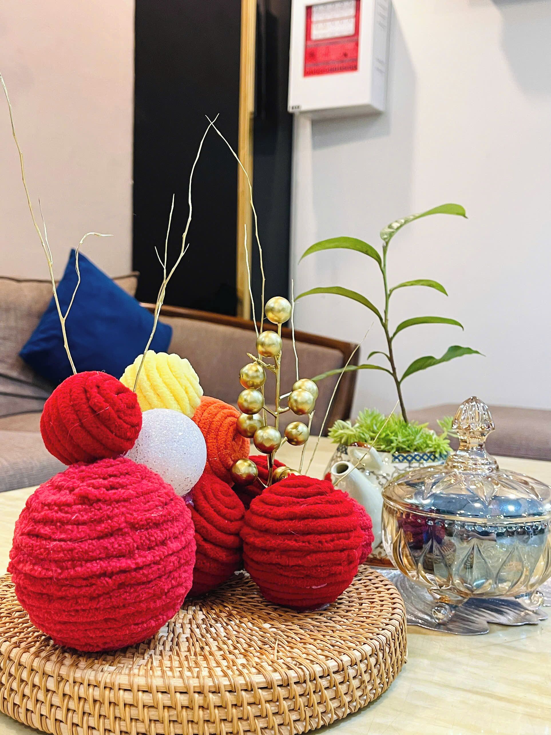 A wicker basket with colorful yarn balls and a decorative glass container on a table.