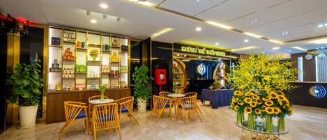 Un moderno vestíbulo de hotel con mostrador de recepción, zona de estar y exhibición de productos locales.