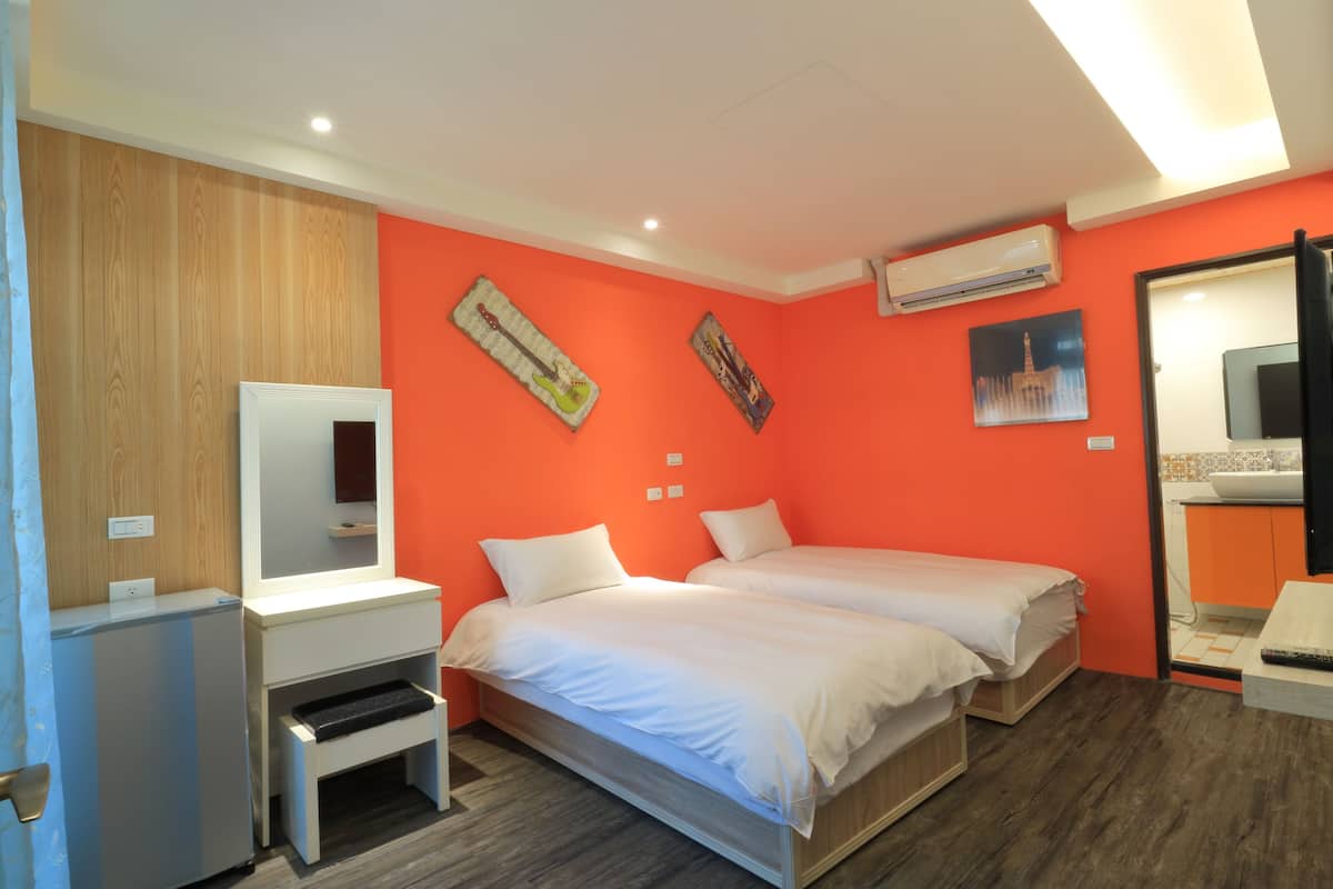 Ein Zimmer mit zwei Betten, einem Schreibtisch, einem Spiegel und einer Klimaanlage.