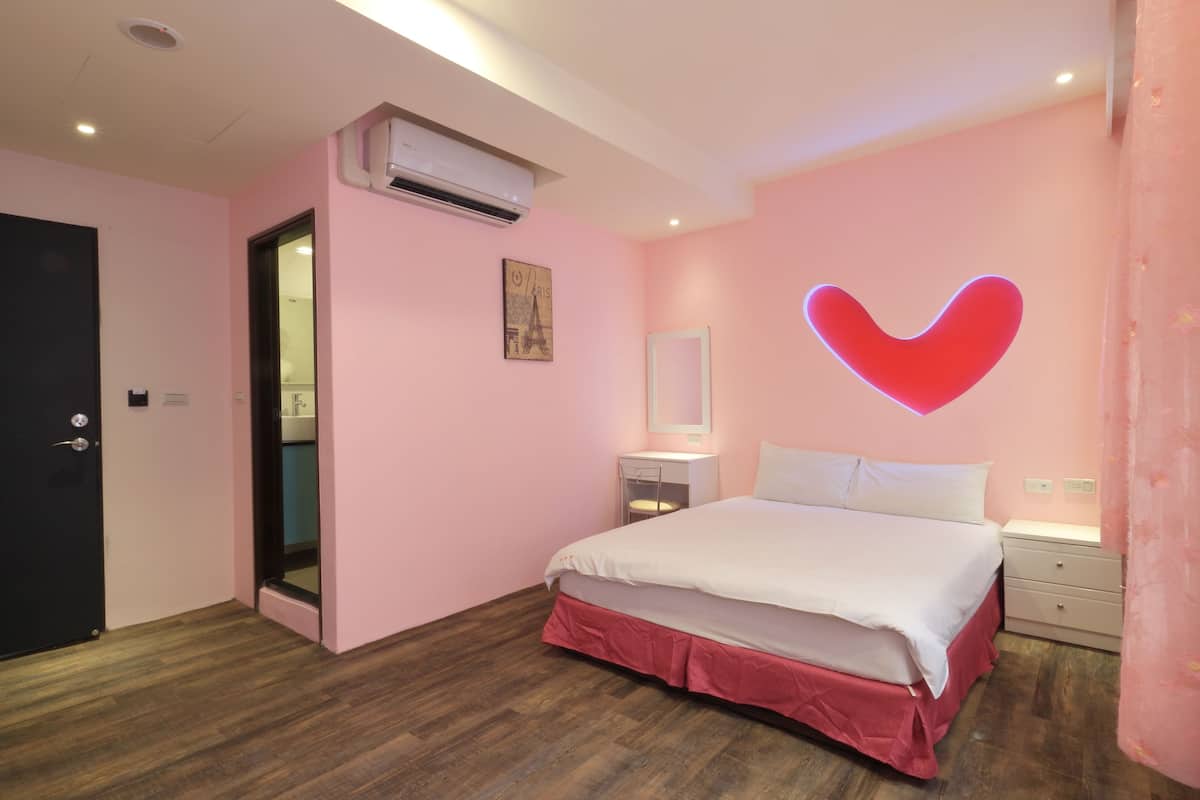 Ein Schlafzimmer mit einem Bett, einem Nachttisch, einem Spiegel und einer Wand-Klimaanlage.