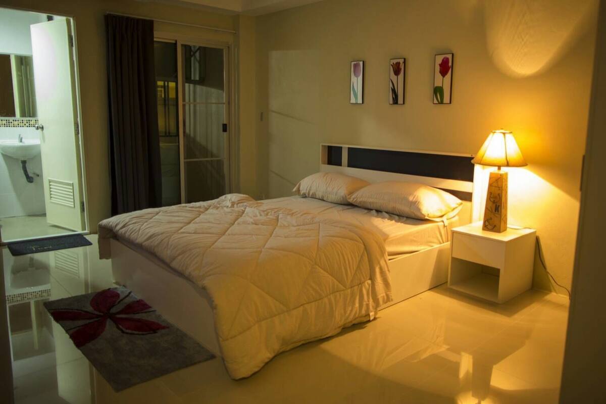 Une chambre d’hôtel avec un lit, une table de chevet, une lampe et une œuvre d’art accrochée au mur.