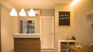 Une petite cuisine agréable, équipée d’une machine à café, d’une petite table et d’une bibliothèque.