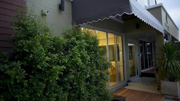 Un bâtiment moderne doté d’une entrée abritée, de grandes portes vitrées et d’une terrasse en bois.