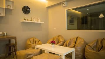 A modern living room with a white table, two bean bag chairs, a clock, and a shelf with decorative items.