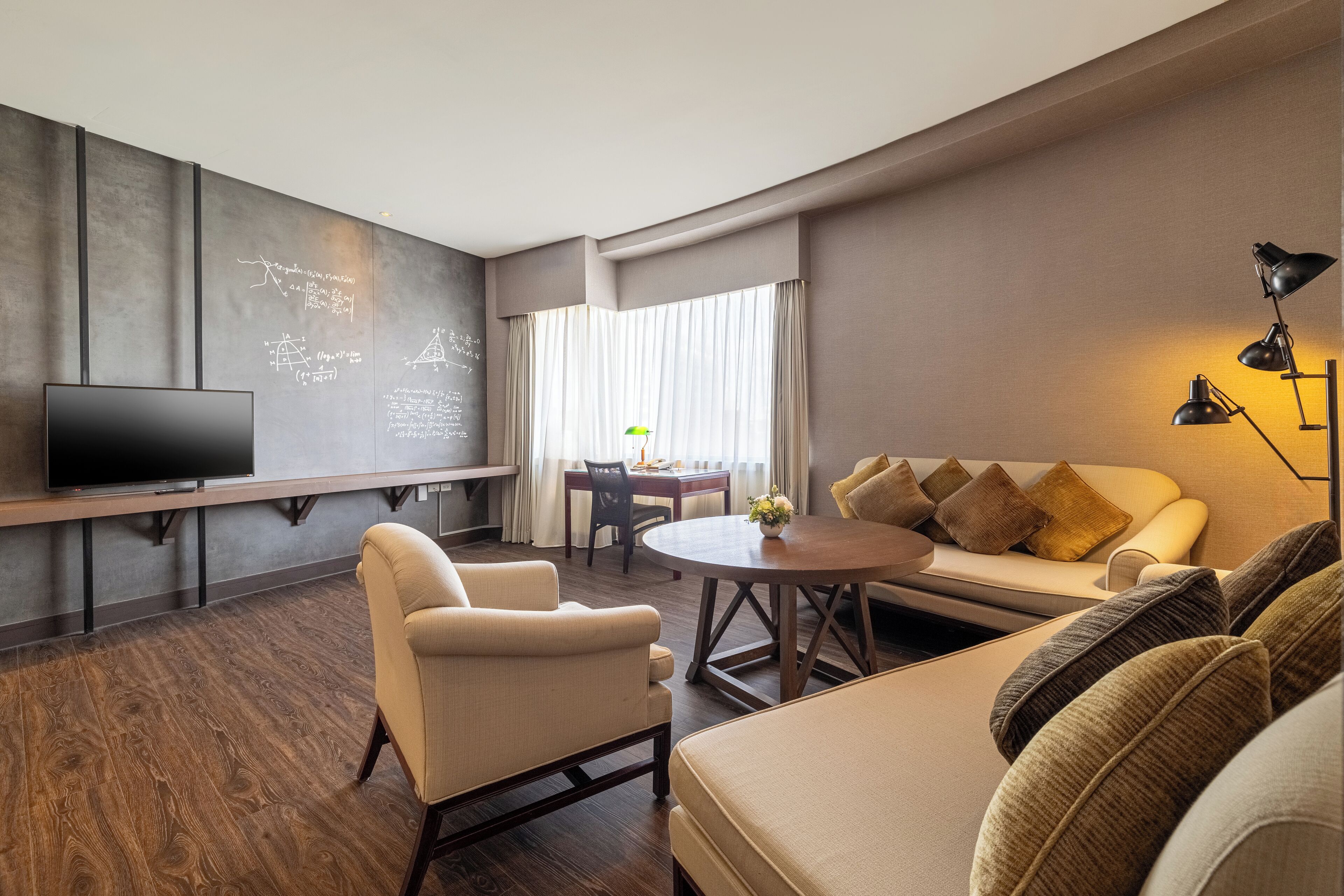 A modern living room with a flat-screen TV, a sofa, a coffee table, and a dining area with a table and chairs.