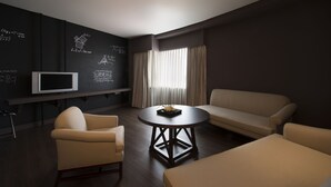 A modern living room with a round table, two sofas, a TV, and a wall with mathematical equations. - Just Sleep Taipei NTU (Taipei)