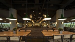 A spacious restaurant with high tables and chairs, hanging pendant lights, and potted plants. - Just Sleep Taipei NTU (Taipei)