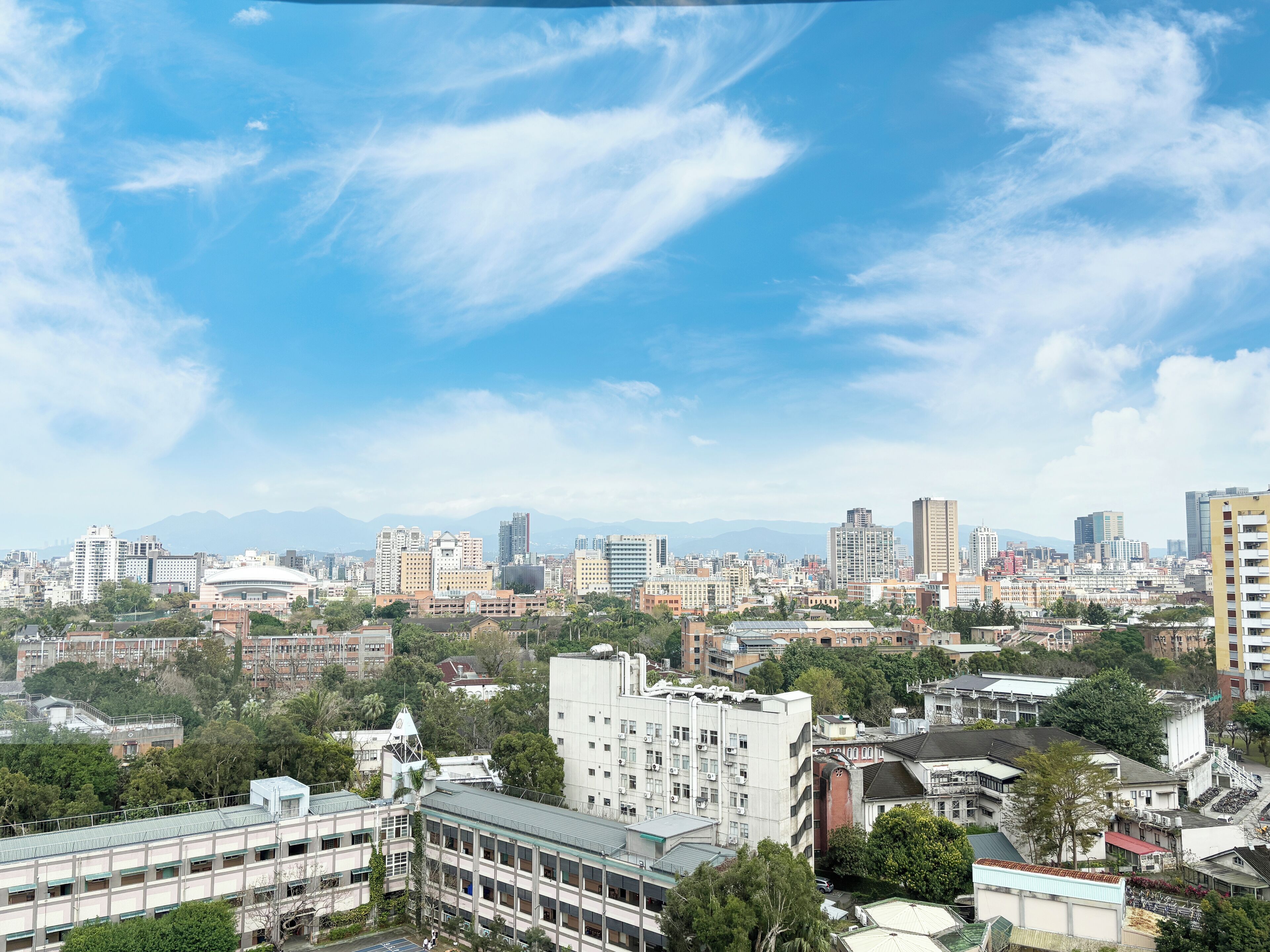 Un horizonte urbano con una mezcla de edificios modernos y antiguos, una estructura en forma de cúpula destacada y un cielo azul despejado.