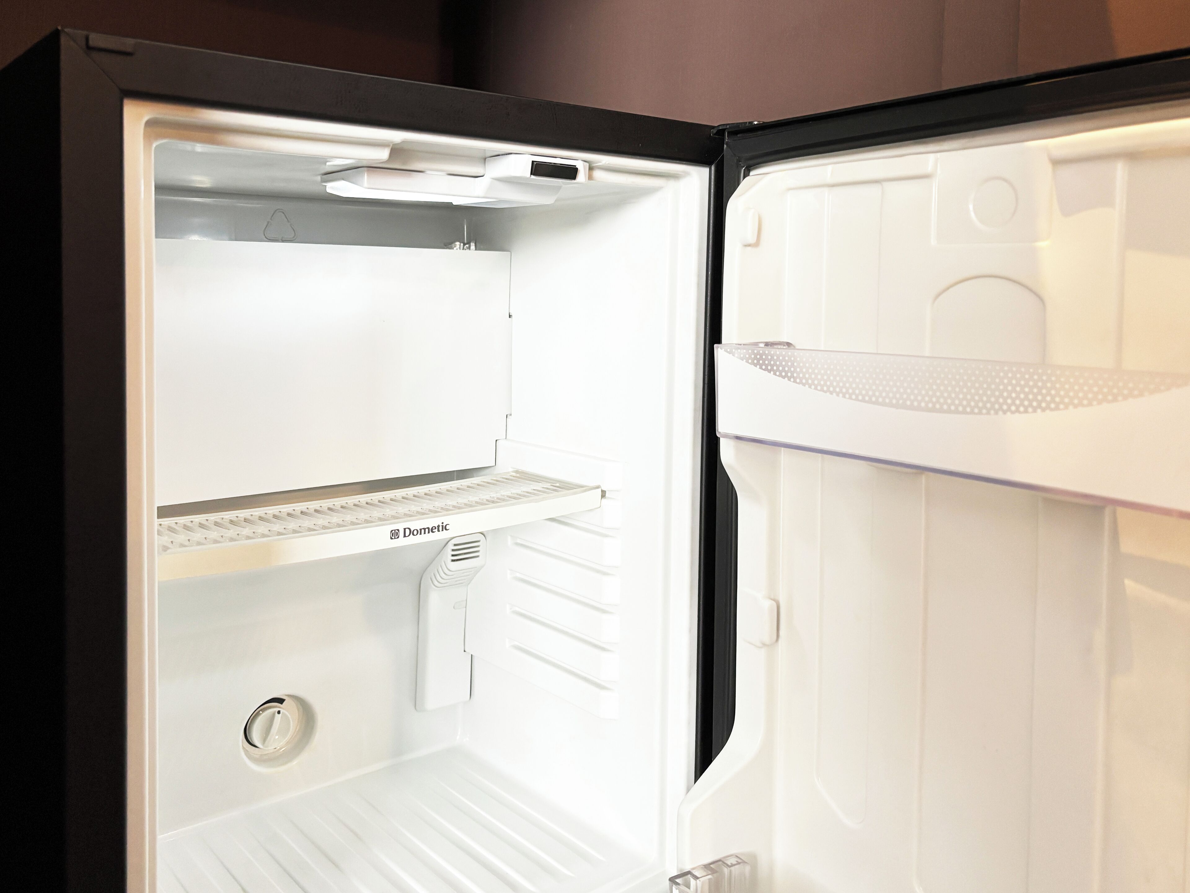 An open refrigerator with a white interior, a control panel, and a freezer compartment.