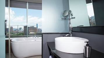 A modern bathroom with a large bathtub, a round sink, and a mirror.