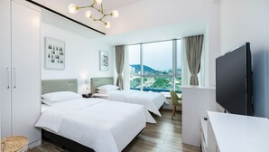 Una habitación de hotel moderna con dos camas, un ventanal con vistas a la ciudad, un televisor de pantalla plana y suelo de madera.