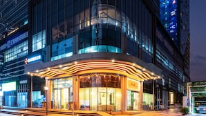 Un hotel moderno con una entrada curva, amplias ventanas de vidrio y una fachada bien iluminada.