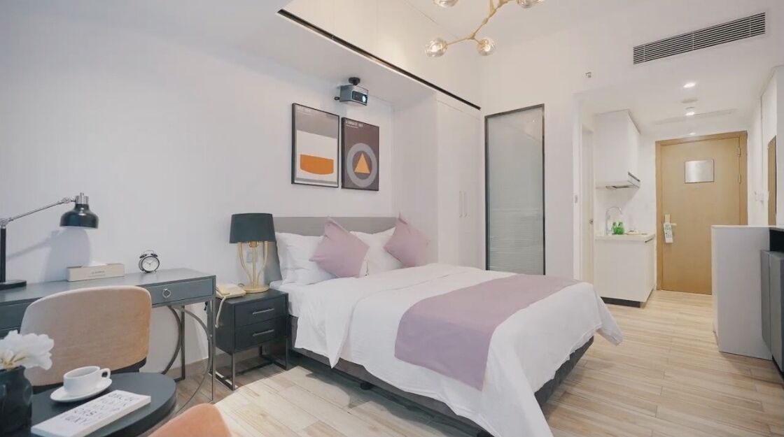 Una camera d'albergo moderna con un letto, una scrivania, una sedia e un comodino.