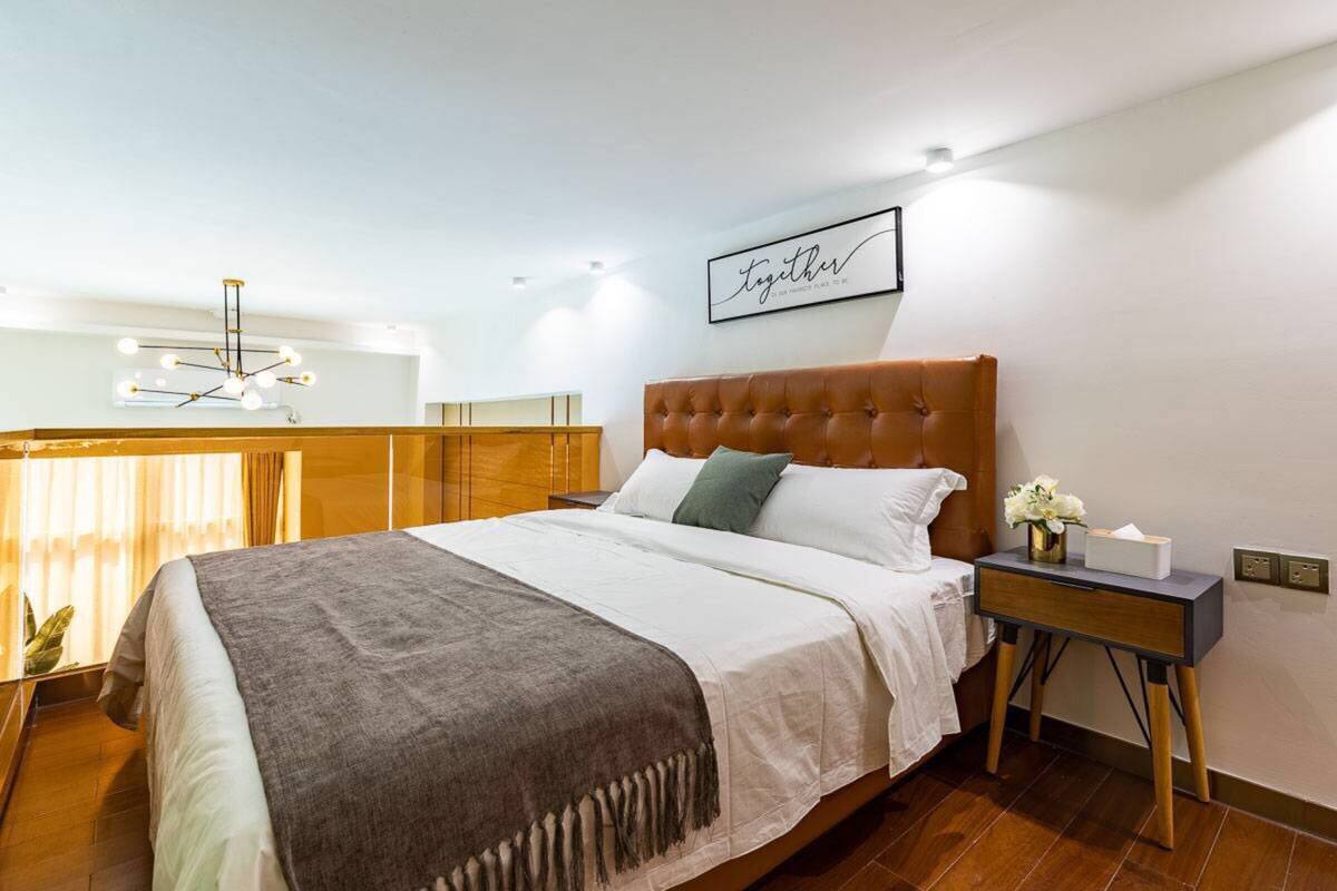 Une chambre à coucher bien aménagée, avec un grand lit, une table de chevet, une œuvre d’art accrochée au mur et un lustre moderne.