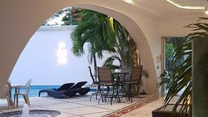 A modern interior with a view of an outdoor pool area, including lounge chairs and a dining table. - Hotel Blue Star Cancun (Cancun)