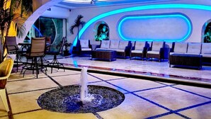 A modern lounge area with a central fountain, seating with a view, and ambient lighting. - Hotel Blue Star Cancun (Cancun)