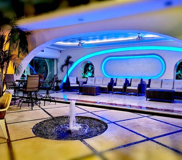 A modern lounge area with a central fountain, seating with a view, and ambient lighting. - Hotel Blue Star Cancun (Cancun)