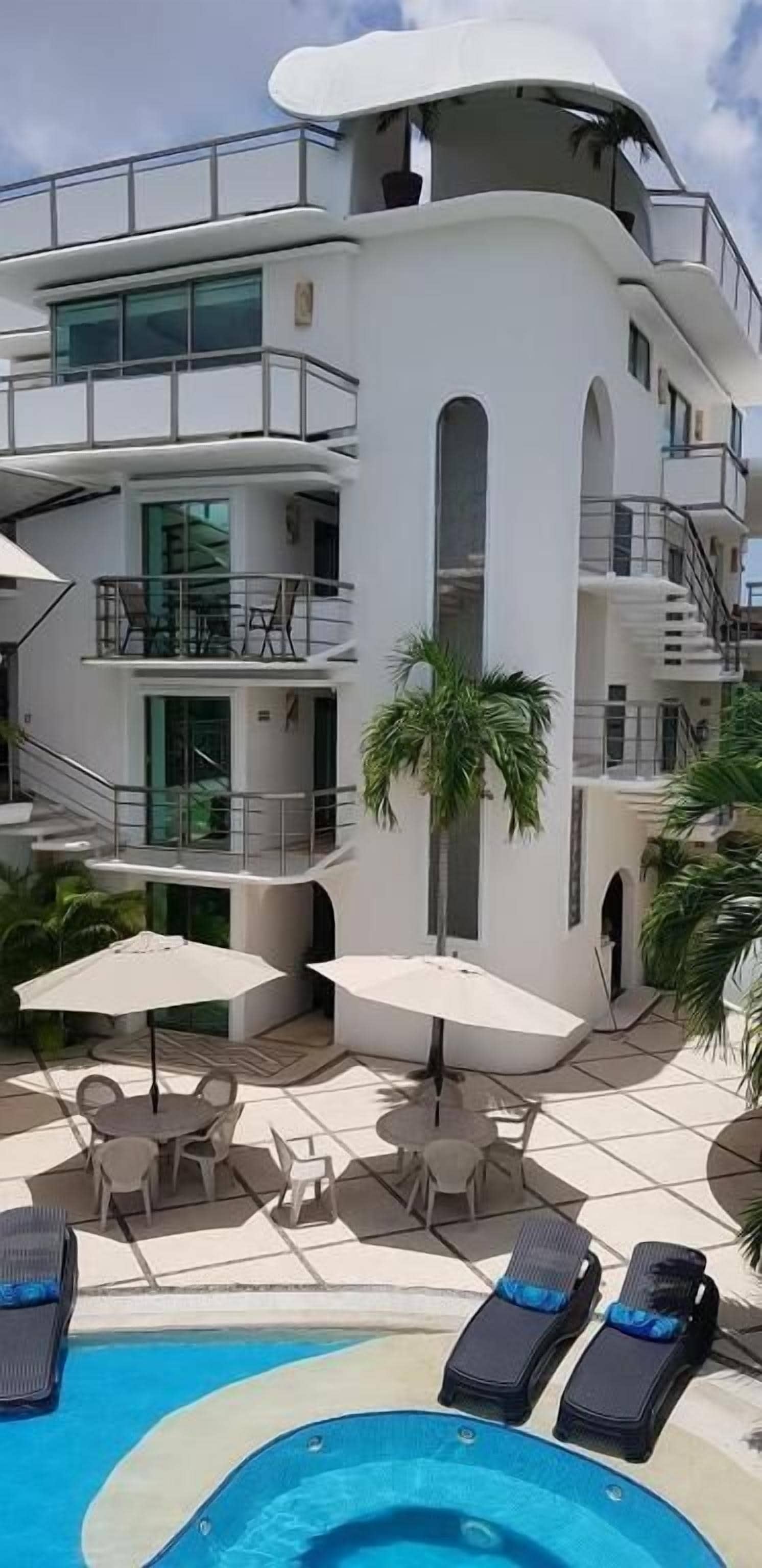 Un moderno edificio de varios pisos con piscina, asientos al aire libre y una escalera que lleva a los niveles superiores.