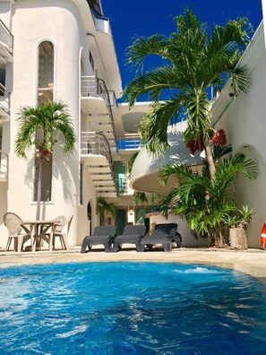 A poolside area with lounge chairs, palm trees, and a clear blue sky. - Hotel Blue Star Cancun (Cancun)