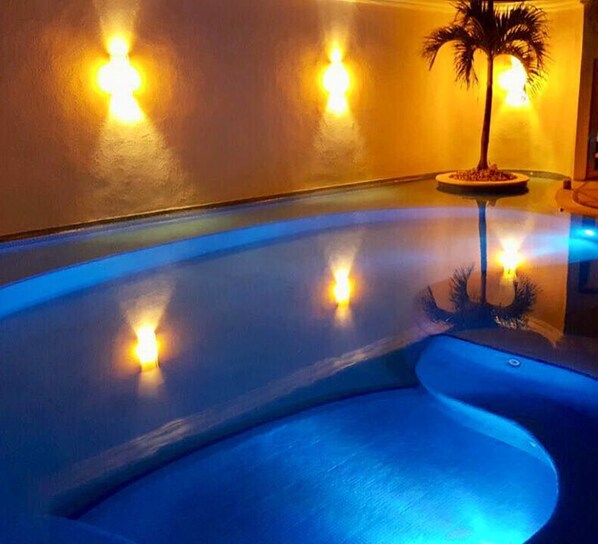A swimming pool with a curved edge and a palm tree in the corner. - Hotel Blue Star Cancun (Cancun)