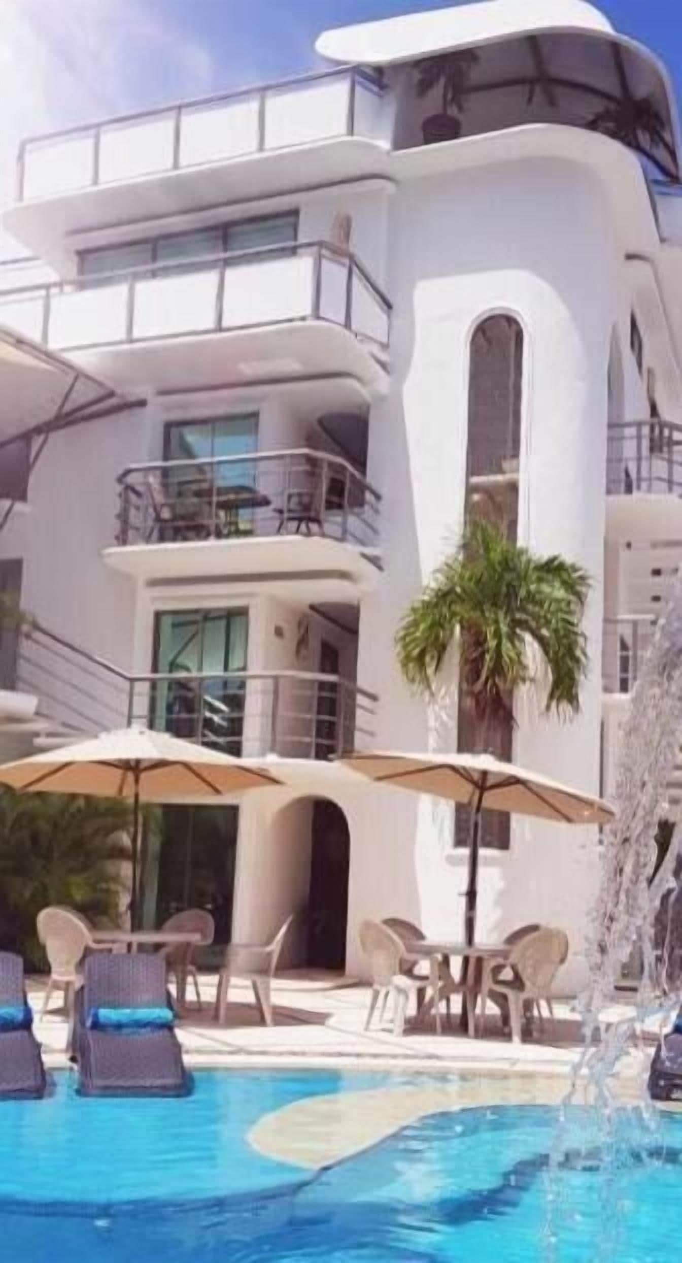 Un edificio moderno con piscina, mobiliario exterior y una fuente.