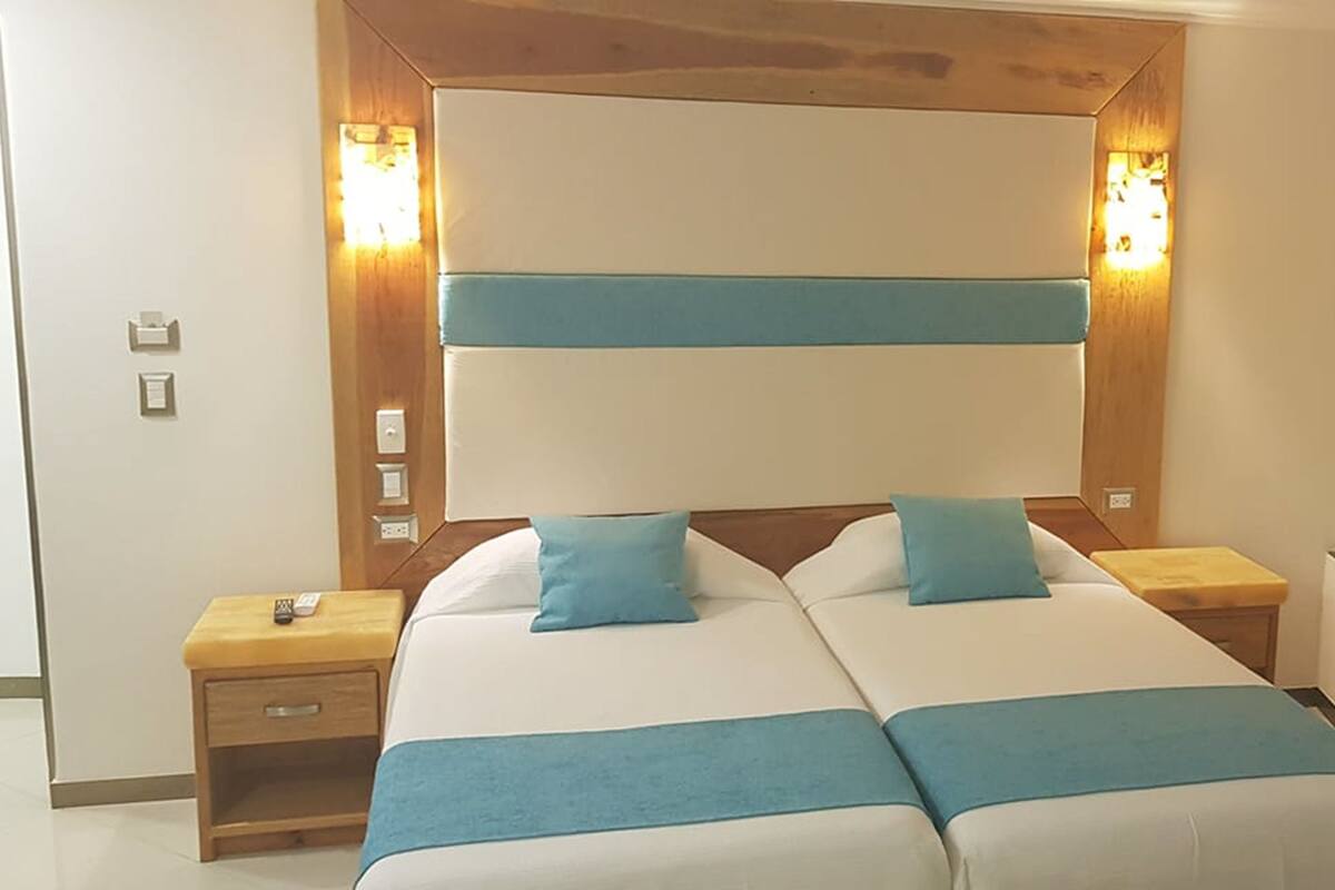 Ein Doppelzimmer mit einem hölzernen Kopfende, zwei Nachttischen und einem Beistelltisch.