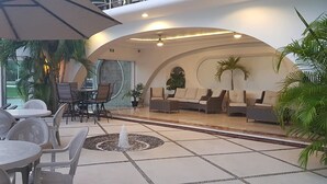 A spacious indoor patio with a seating area, tables, and chairs. - Hotel Blue Star Cancun (Cancun)