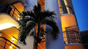 A modern building with a curved facade, a central vertical window with a decorative pattern, and balconies with railings. - Hotel Blue Star Cancun (Cancun)